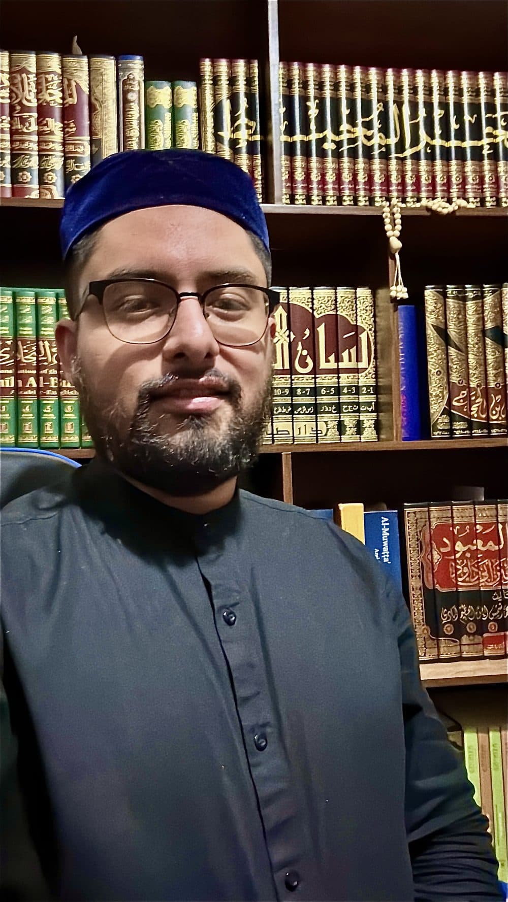 Mullah Khalid frente a su biblioteca de obras clásicas en árabe